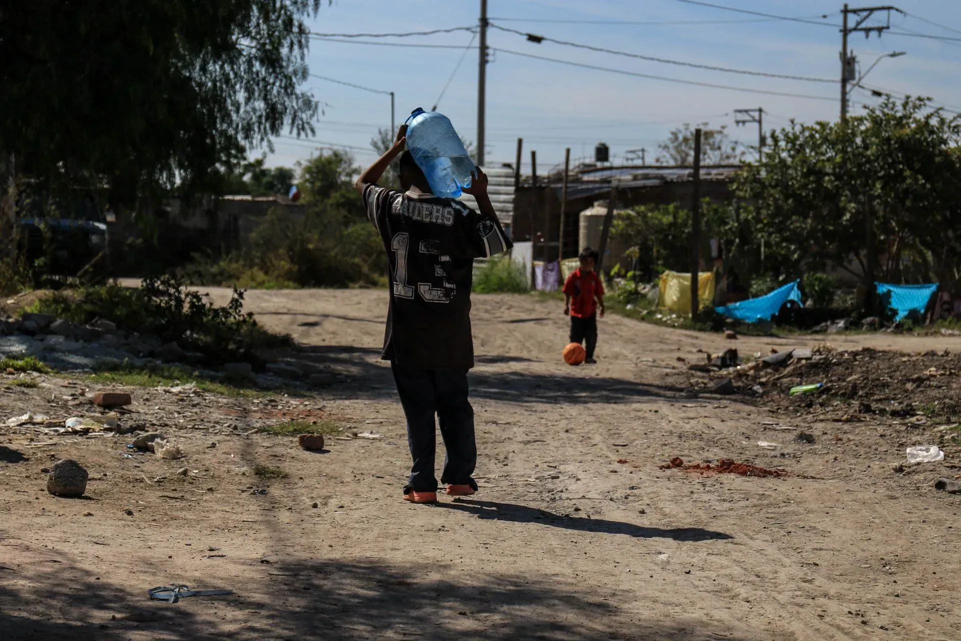 A boy carries a demijohn of water on his shoulders for his family in the community of San Juan de Abajo, in León, Guanajuato. Credit: Credit: Juan José L. Plascencia